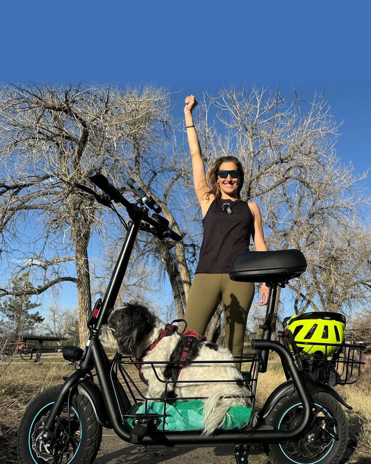 woman using seated electric scooter while walking dog in park